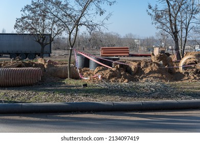 Dug Ditch. Piping, Concrete Well Rings And Corrugated Pipes. Construction Industry. Daytime. Outside.