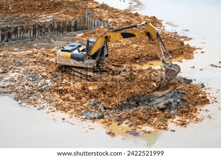 dug in the river bed. Yellow well works on the river bank, Excavator works on the river, bucket. bridge construction design, Unsuitable material or dirt, working on construction site.