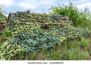 The dugout for hiding soldiers is covered with a camouflage net. The use of camouflage in military operations