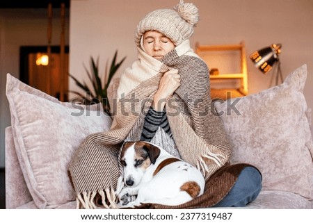 Dull middle aged woman save herself from freezing wear winter clothes muffle up in blanket think of buying radiator heater. Shivering young lady sit on sofa in plaid ponder on much too cold at home
