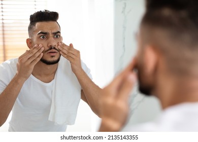 Dull Skin Concept. Worried Arab Guy Looking At Mirror And Touching Face, Shocked Young Middle Eastern Man Examining Dark Circles Under Eyes While Standing In Bathroom At Home, Selective Focus - Shutterstock ID 2135143355