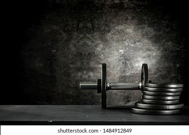 Dumbbell, Barbell And Workout In The Gym. Copy Space On Black Grunge Wall And Board Background.