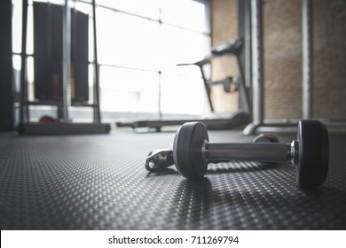 Dumbbell And Rope On The Floor In The Gym With Treadmill In Background