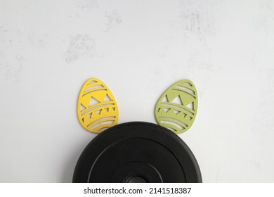 Dumbbells barbell weight plate disc and decorative Easter eggs in shape of bunny ears. Healthy fitness lifestyle rabbit composition, gym workout and training concept. Fit flat lay with copy space. - Shutterstock ID 2141518387