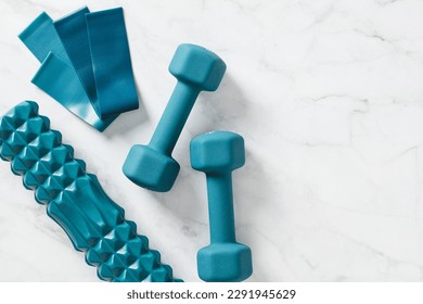 Dumbbells, elastic band and roller on marble background. Workout equipment top view - Shutterstock ID 2291945629