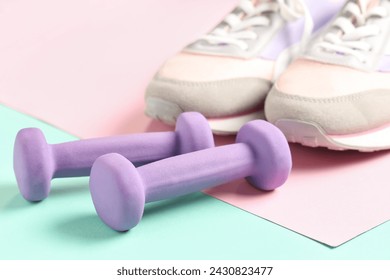 Mancuernas y zapatos deportivos sobre fondo de color, primer plano