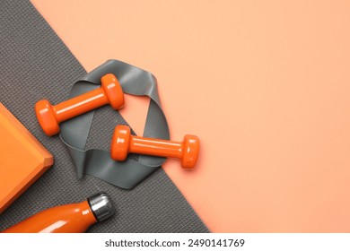 Dumbbells, thermo bottle, fitness elastic band, yoga block and mat on coral background, flat lay. Space for text - Powered by Shutterstock