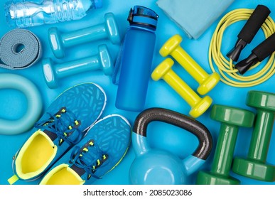 Dumbbells, trainers, jumping rope and other fitness equipment on blue background, top view - Shutterstock ID 2085023086