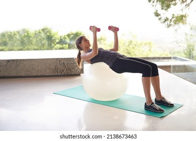 The Dumbell Press. Shot Of An Attractive Young Woman Working Out In A Studio With A View.