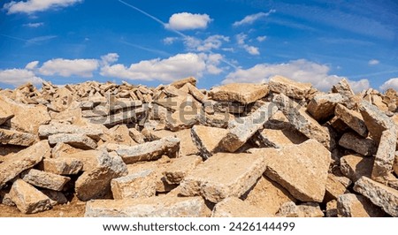 Dump of concrete debris piles on the ground in vineyards area nature with cloudy sky. large pile of concrete scraps. concrete blocks are piled up on the mounds.