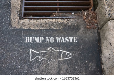 Dump No Waste And The Outline Of A Fish Stenciled On The Blacktop Of A Parking Lot Near A Storm Drain