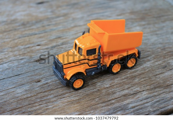 Dump toy\
truck yellow color on wooden\
background