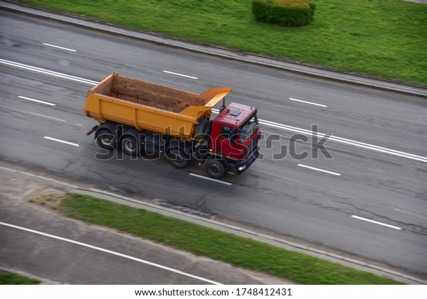Dump truck\
carries sand along a road in a city. View from above. Object in\
motion, soft focus, possible\
graininess