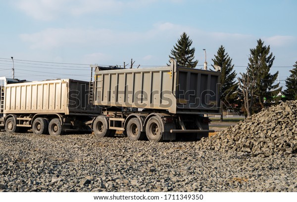 A\
dump truck is dumping gravel on a construction site. Dump truck\
dumps its load of gravel on a new road construction project. Road\
building. Preparing of the fundament for a\
asphalting.