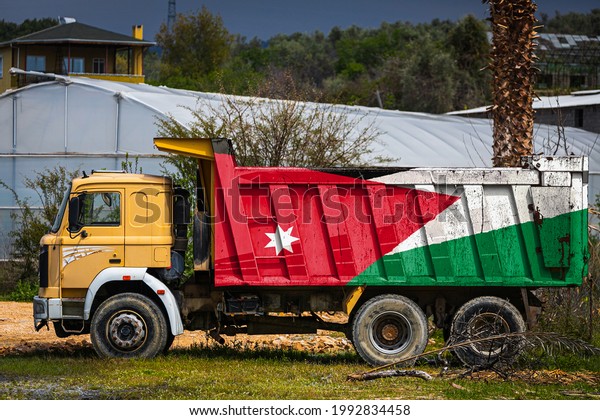 Dump truck with the image of the national flag of\
Jordan is parked against the background of the countryside. The\
concept of export-import, transportation, national delivery of\
goods