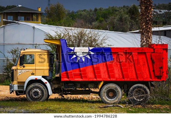 Dump truck with the image of the national flag of\
Taiwan is parked against the background of the countryside. The\
concept of export-import, transportation, national delivery of\
goods