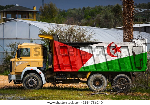 Dump truck with the image of the national flag of\
West Sahara is parked against the background of the countryside.\
The concept of export-import, transportation, national delivery of\
goods