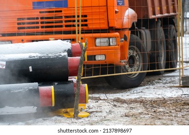 A Dump Truck With A Red Cab Stands On A Construction Site In Winter Near New Water Pipes. A Road Dump Truck For Transporting Soil.