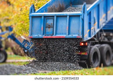Dump truck, tractor and bulldozer unloading gravel, road metal and crushed stone cement material during landscaping improvement and new pedestrian walk road construction site