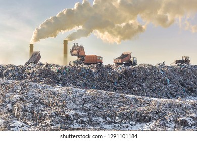 Dump trucks unloading garbage over vast landfill. Smoking industrial stacks on background. Environmental pollution. Outdated method of waste disposal. Survival of times past - Shutterstock ID 1291101184