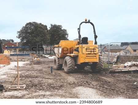 Dumper parked next to profiles set by site engineer for levels for new access road construction on new residential housing development construction site