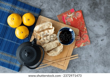 Dumpling with sauce on bamboo board and marble backdrop with Chinese New Year decoration. Asian cuisine. Copy space. Top view.