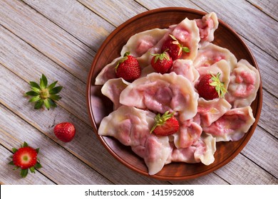 Dumplings, filled with strawberries. Varenyky, vareniki, pierogi, pyrohy - dumplings with filling. View from above, top studio shot