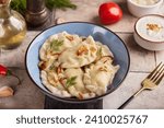 Dumplings, pierogi or vareniki with potato or meat filling. Served with dill, roasted onion and sour cream sauce. Polish or Ukrainian cuisine. Delicious homemade dish.