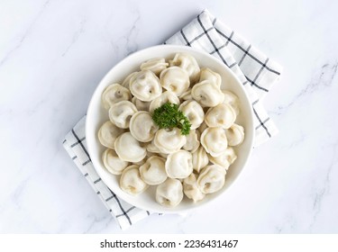 Dumplings or russian pelmeni with meat and bay leaf on a white background. Top view. Selective focus