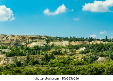 Dumps of processed iron ore with growing green plants. Waste from the iron ore industry. Belgorod region, Russia.