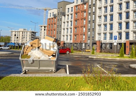 Dumpster for Demolition Removal. Container for construction waste, dumping renovation waste. Metal tank for construction garbage. MSW container. Modern complex of multi-apartment residential building