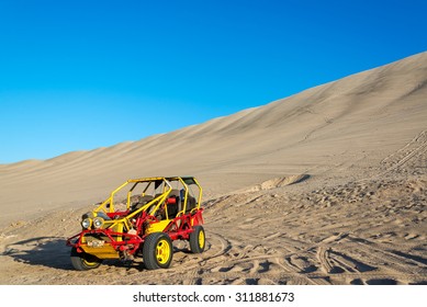 Dune Buggy At The Foot Of A Large Sand Dune In Huacachina, Peru