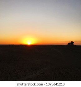 A Dune Buggy Silhouette In The Desert At Sunset.