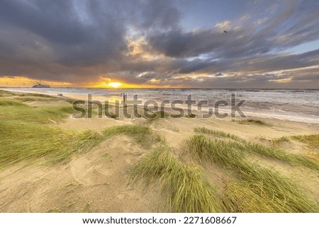 Dune Landscape under cloudy autumn sky. Dark clouds blowing over setting sun. Wijk aan Zee, North Holland. Netherlands. Marine landscape of nature of Europe.