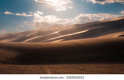 dunes in the desert with a cloudy day, blue sky and foot prints. - Powered by Shutterstock