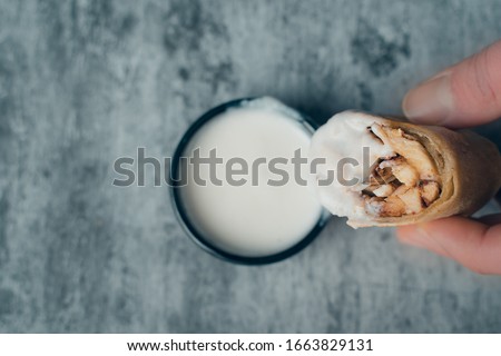 Dunking slice shawarma in sauce dip with hand
