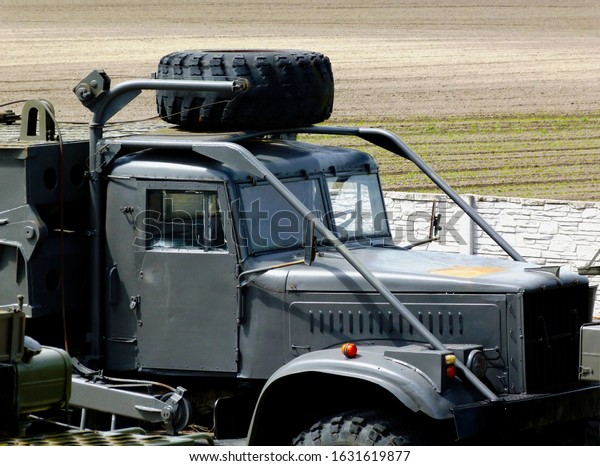 Dunvarsany, Hungary - 05.11.2019: Old second\
World War gray military truck detail with black spare tire on top\
of the driver`s cab and protective steel frame, spare diesel tank\
with light\
background
