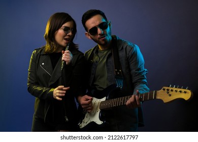 Duo of musicians enjoying performing during a rock and roll concert. Female singer and guitarist rehearsing