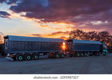 Duo-trailer with tippers for scrap metal parked at sunset.