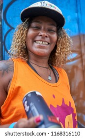 Duque De Caxias, Rio De Janeiro, Brazil -  December 10, 2018: Brazilian Curly Afro Hairstyle Model Woman Artist  Holding Spray Can Aerosol Smiling In Favela Slum