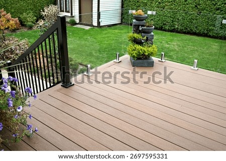 Durable deck solution with composite boards and glass panels as railings on residential home improvement project.