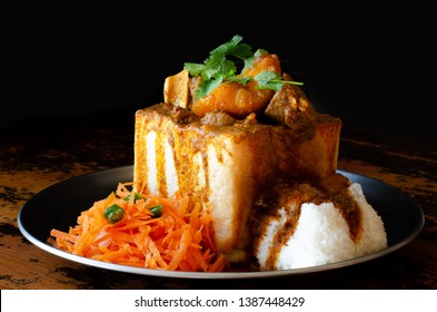 A Durban Bunny Chow - or a quarter mutton bunny - served with sambals. This is an iconic Durban meal consisting of a section of a loaf of bread hollowed out and filled with mutton curry and gravy.  - Shutterstock ID 1387448429