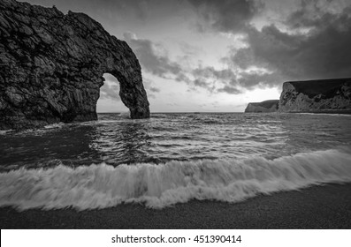 Durdle Door on the Jurassic coast of Dorset with crashing wave in Black and White