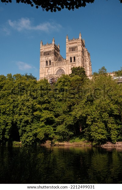 Durham\
England: 2022-06-07: Durham Cathedral exterior during sunny summer\
day. View from river wear with lush green\
trees