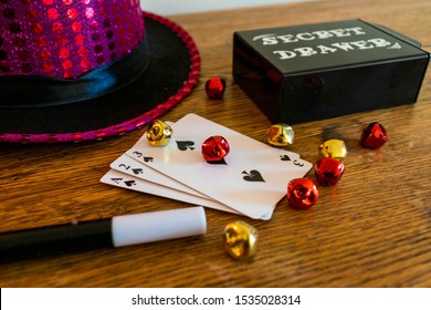 Durham, UK - 18 October 2019: Magic Show Magicians Trick Concept Background. Children's Magic Box With Sequined Top Hats, Magic Wand, Playing Cards, Cup And Ball Trick, Secret Drawer Box And Die.