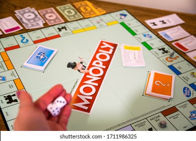 Durham, UK - 5 April 2020: Monopoly Is The Classic Fast-dealing Property Trading Board Game (Hasbro Games). Financial, Banking, Buying Property, First Home Concept. Women Rolls Dice