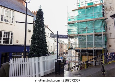 Durham, UK - Nov 2016: View Of Direction Signpost And Christmas Tree With White Fence At Street Intersection With Commercial Buildings And Renovated Building And Bright Sky Background. No People.