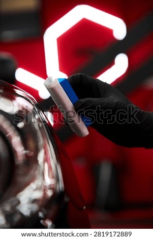 During ceramic coating application, applying liquid glass sealant to black car hood for scratch resistance. Applying ceramic paint protection to restore and preserve vehicle aesthetics.