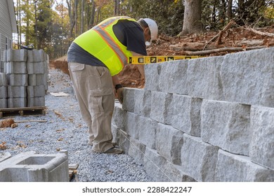 During construction of new home at near construction site construction worker was laying concrete blocks for retaining wall.