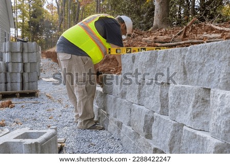 During construction of new home at near construction site construction worker was laying concrete blocks for retaining wall.